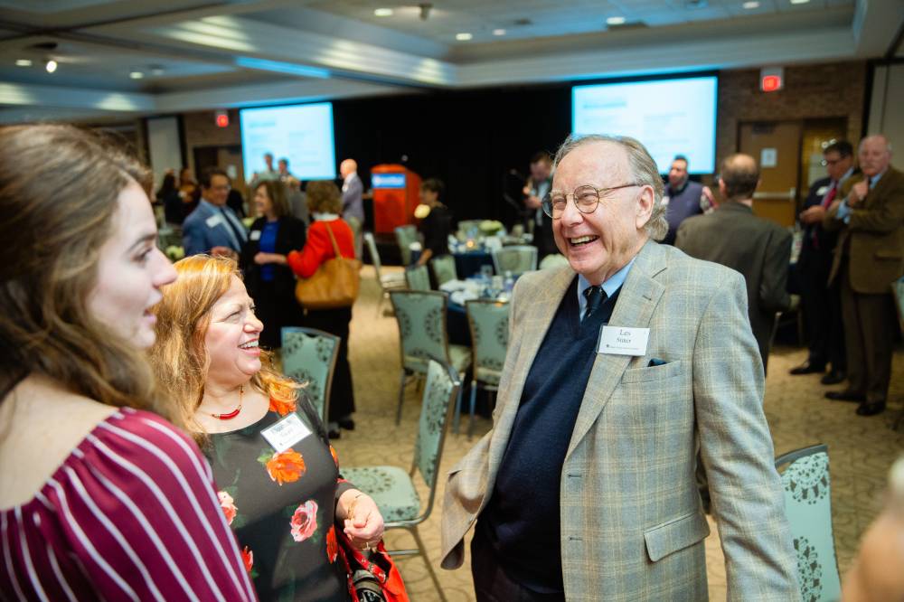 Guest laughing while chatting with two other guests at Scholarship Dinner 2019